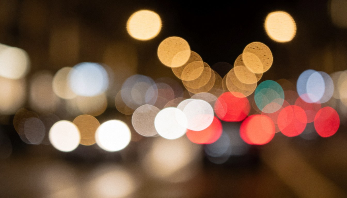 Warm toned bokeh background of blurred city car lights at night, suitable for text overlays and graphic design projects.