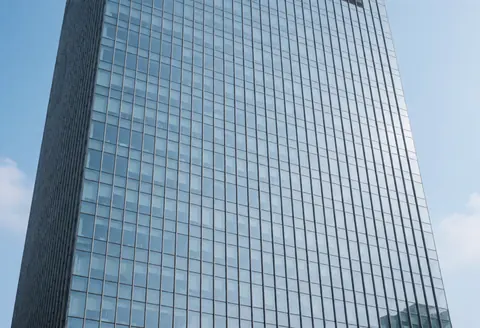 Close-up of a modern building facade with large glass windows reflecting the clear blue sky, ideal for window cleaning services.