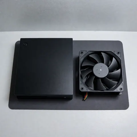 Black video game console and a new replacement fan on a dark surface, ideal for console repair services
