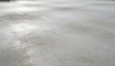 Smooth gray concrete texture with natural light, serving as a neutral background for tennis court installer text and promotional content
