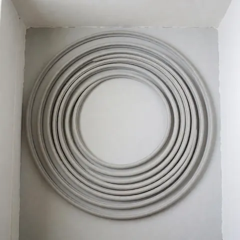 Spiral rubber gasket on light gray background, ideal for refrigerator repair. Uniform texture and clean edges, neutral natural lighting, perfect for showing product in new condition ready for installation.