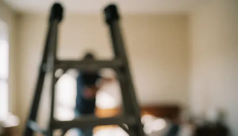 Out-of-focus ladder in the foreground with a blurred background of walls and room, suitable for wall repair text overlays
