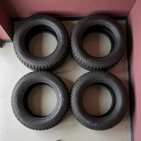 Four new camper tires in good condition inside a garage with pink walls, viewed from above, ideal for repairs.