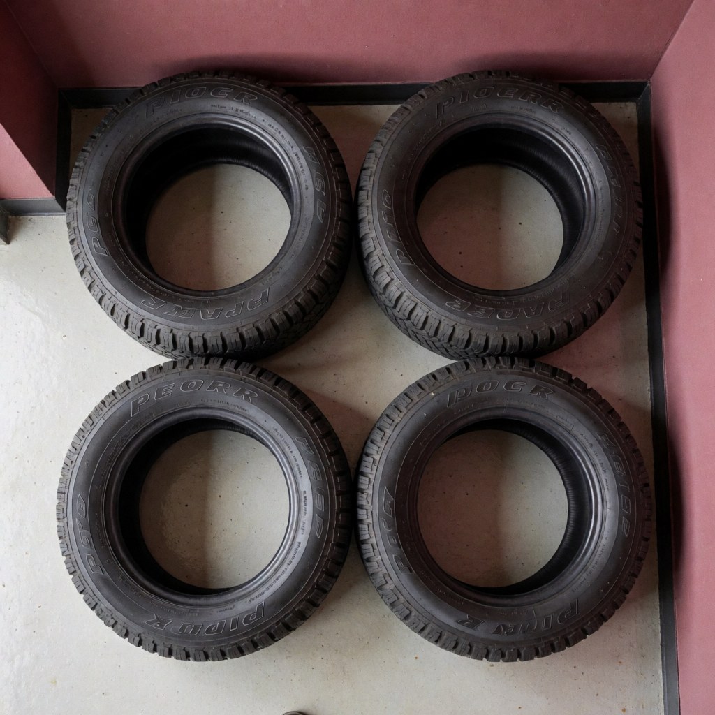 Four new camper tires in good condition inside a garage with pink walls, viewed from above, ideal for repairs.