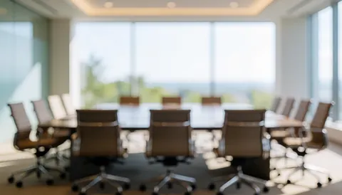 Bright modern meeting room with empty tables and chairs, illuminated by natural light, suitable for presentations or corporate text backgrounds