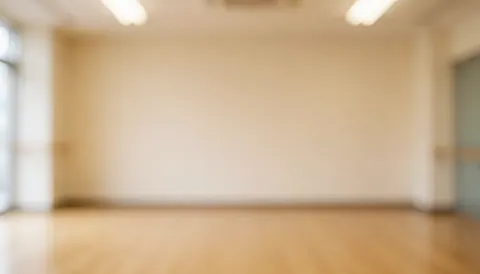 Warmly lit beige dance studio with wooden flooring, ideal for text or logos, no people or recognizable details.