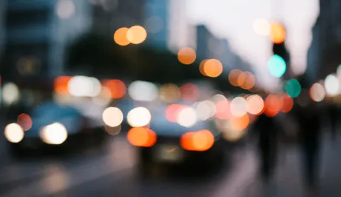 Abstract background of an urban street with blurred car and streetlights in warm and cool tones, ideal for overlaying business text.