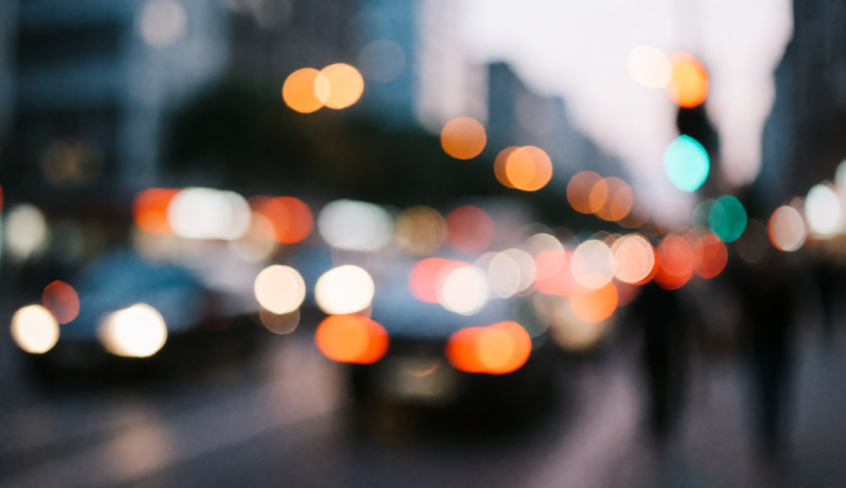 Abstract background of an urban street with blurred car and streetlights in warm and cool tones, ideal for overlaying business text.