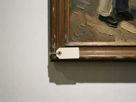 Detailed view of a textured oil painting in a wooden frame with a white price tag hanging from it.