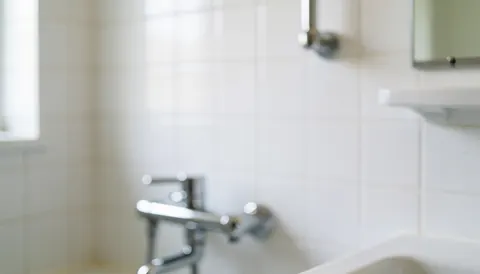 Soft focus background of white ceramic tiles and a chrome faucet with natural light, suitable for plumbing service text overlays