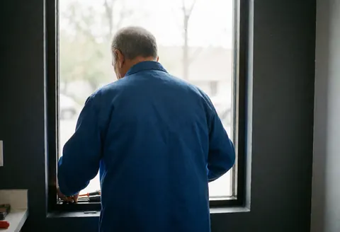 Close-up of hands installing sealant on a window frame during a repair service