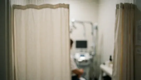 Out-of-focus medical office interior featuring a shower curtain and blurred medical equipment in the background, suitable for text overlay.