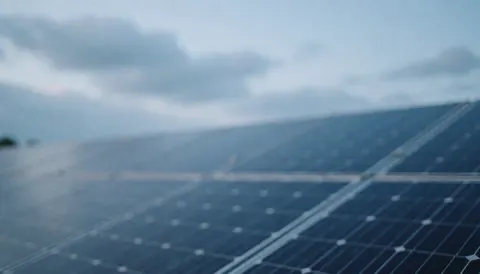 Out of focus photovoltaic solar panels against a soft blue cloudy sky, suitable as a professional background for text or service banners.