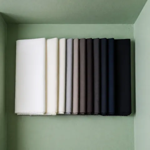 White to black gradient sewing fabric samples arranged on a soft green wall, ideal for tailor shop displays