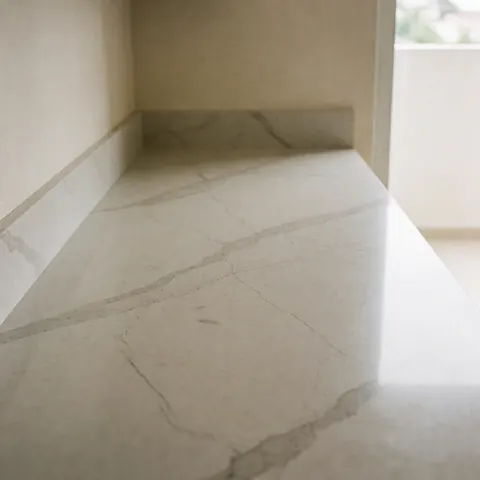 Polished gray veined quartz countertop with natural light in a modern kitchen featuring beige walls and a clean surface