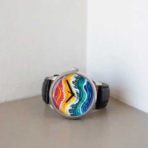 Close-up of a wristwatch featuring a vibrant tropical wave dial and black strap on a neutral surface with natural lighting