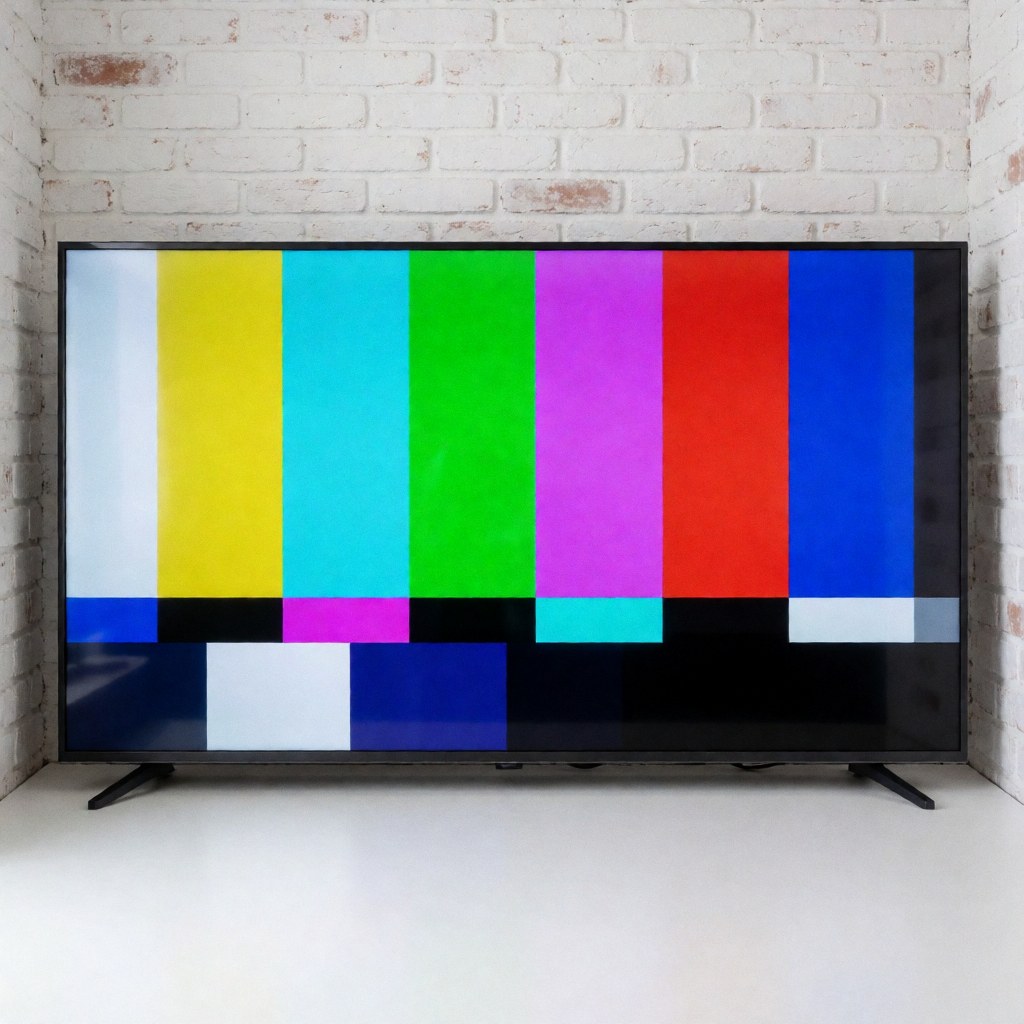 Large television displaying a color test pattern with a white painted brick wall background showing image quality