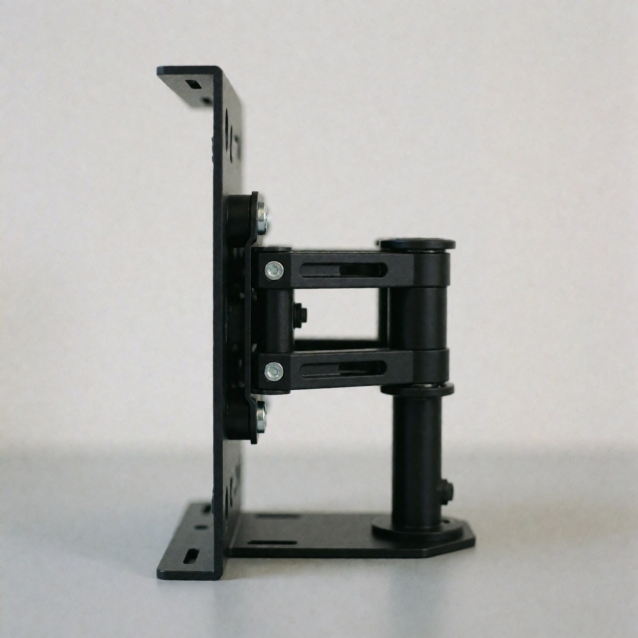Black universal tv mounting bracket with adjustable arms and visible screws on a gray surface