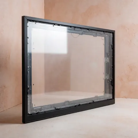 New TV panel with matte black frame and transparent internal structure on neutral surface with soft studio lighting