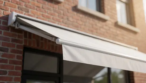 White awning installed on red brick wall with warm lighting, serving as a professional background for text.