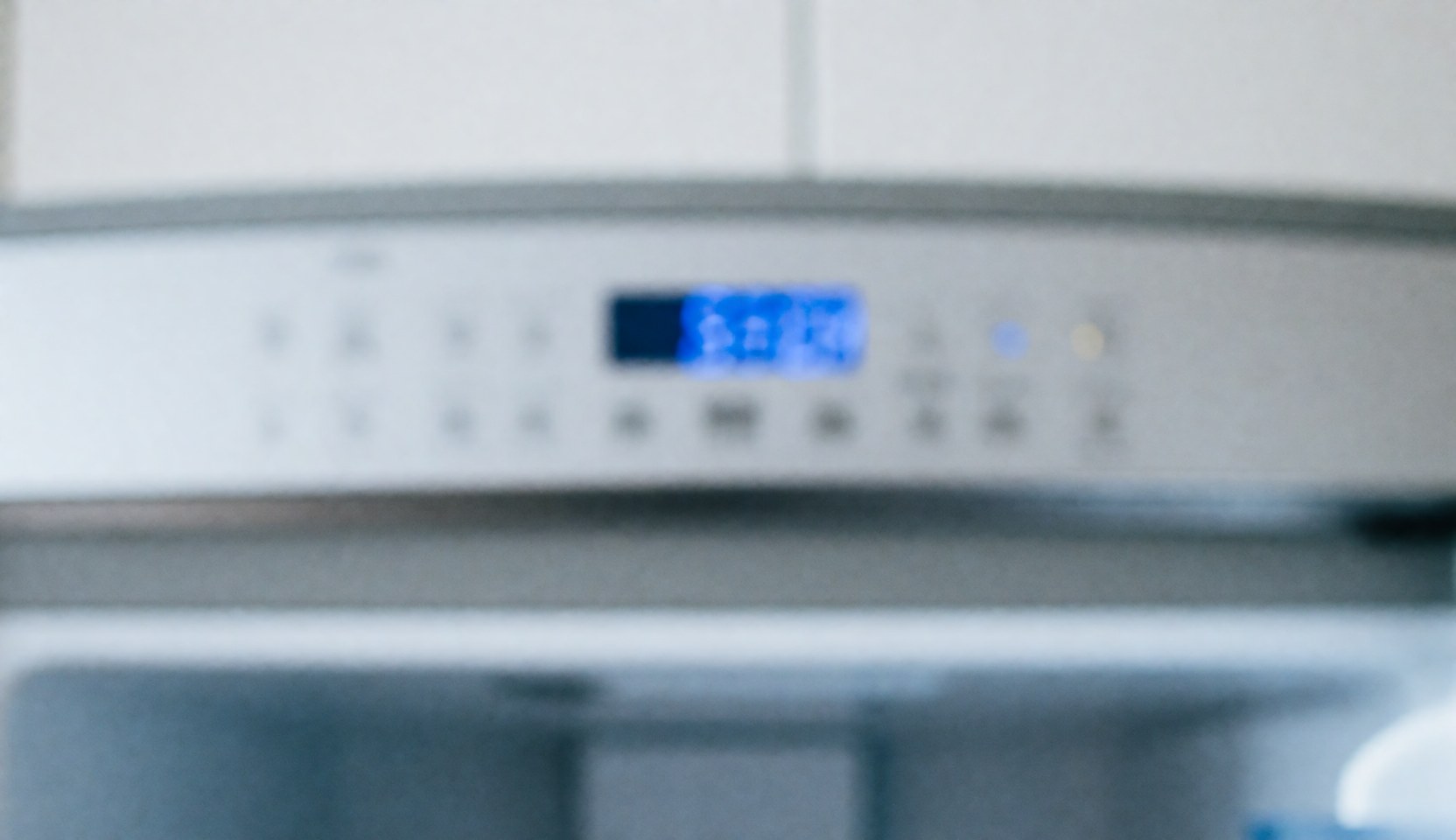 Close-up of a refrigerator control panel illuminated by soft blue light, serving as a clean professional background for text overlay.