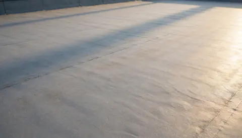 Gray flat roof texture with soft sunset shadows, ideal for commercial text backgrounds without distractions.