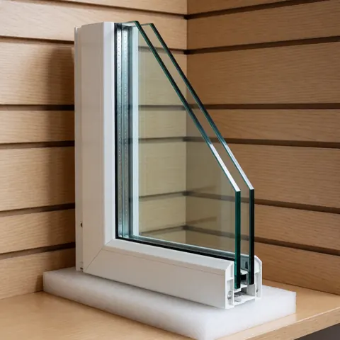 White double glazed window frame resting on protective foam against a light wood wall, ready for home installation.
