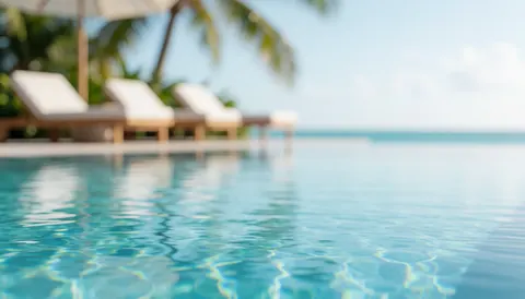 Blurred background of an infinity pool with beach chairs and palm trees, ideal for luxury vacation text overlays