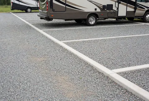 Gravel RV parking lot with clearly marked white lines showing organized spaces for recreational vehicles