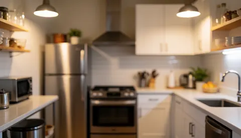 Hostel kitchen featuring stainless steel appliances, white cabinets, wooden shelves, and warm lighting, ideal for text backgrounds.