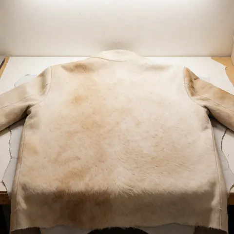 Cowhide leather with natural texture on a workbench in a workshop with bright lighting and a warm background wall for upholsterers