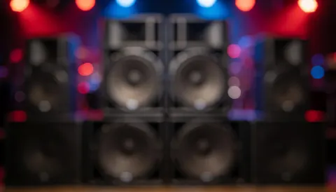 Stage speakers with blurred red and blue background lights, ideal for text overlay