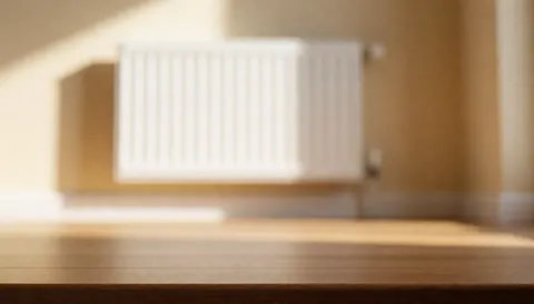 Close-up of a newly installed white radiator against a beige wall with wooden flooring and warm ambient light, suitable for text overlay.