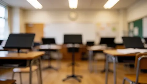 Blurred music classroom background featuring wooden desks, music stands, and hardwood flooring, illuminated by natural and artificial light, ideal for text overlay.