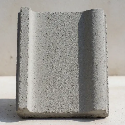 Close-up of a rectangular gray concrete tile with a distinct granular texture, showcasing its modern design under natural lighting.