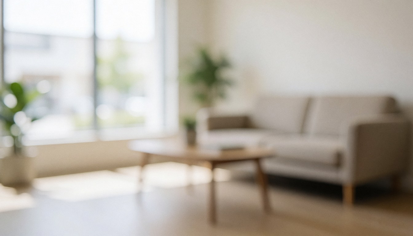 Modern waiting room background featuring a beige sofa, wooden coffee table, and plants with soft natural lighting, ideal for advertising text overlay.