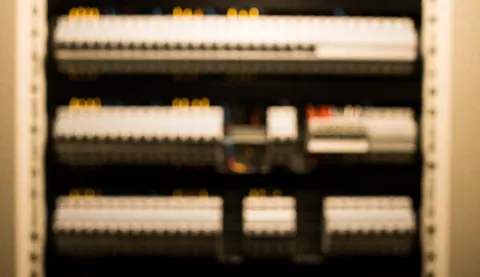 Out-of-focus background of an elevator electrical panel with switches and terminals, suitable for technical service text overlays.