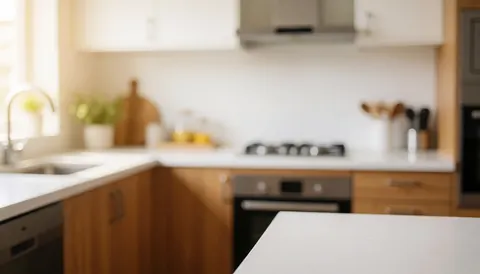 Modern kitchen featuring a white countertop and wooden cabinetry with blurred background suitable for text overlay