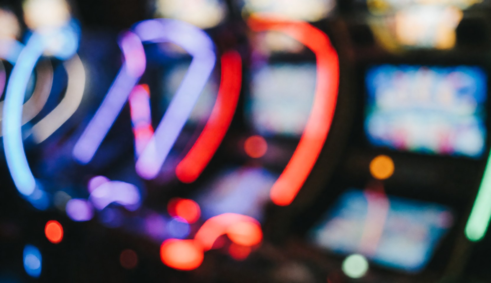 Abstract background of an amusement park center with red, blue, and purple game lights creating a bokeh effect, ideal for text overlays.