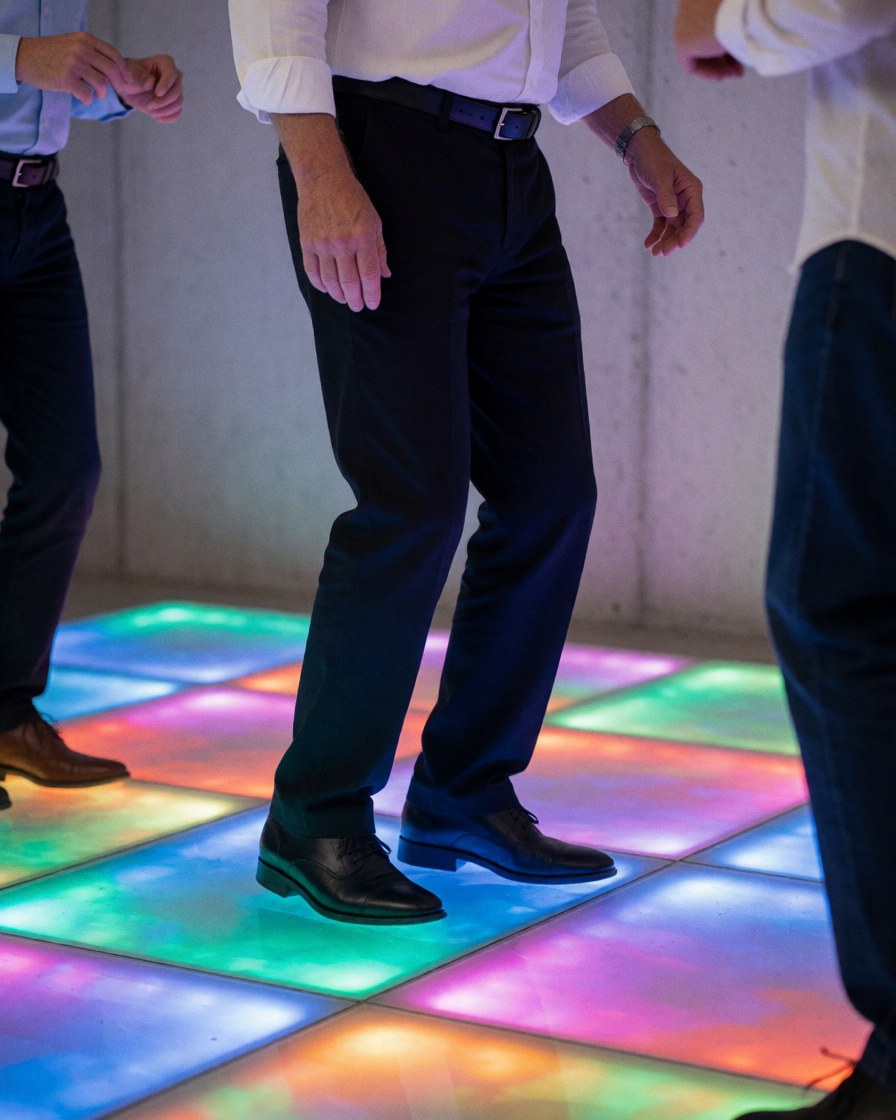 Adult feet standing on an illuminated event floor with changing LED lights and concrete walls in a vibrant professional atmosphere