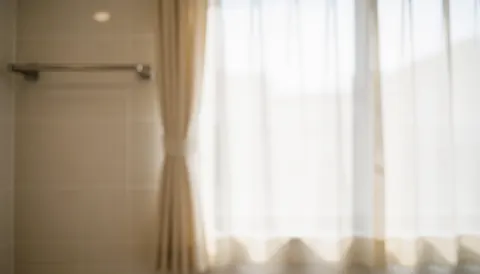 Soft focus bathroom scene featuring translucent curtains, tiled walls, and a metal towel rack, suitable for professional text overlays.