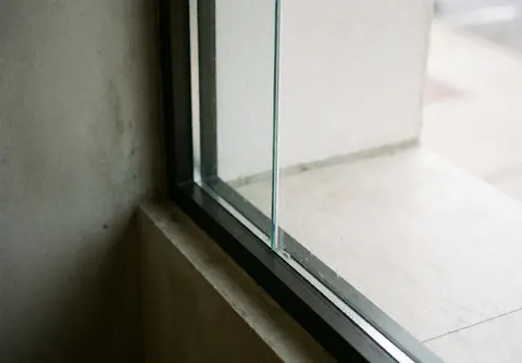 Spotless commercial window with black frame and concrete wall, illuminated by natural light, ideal for window cleaning services.