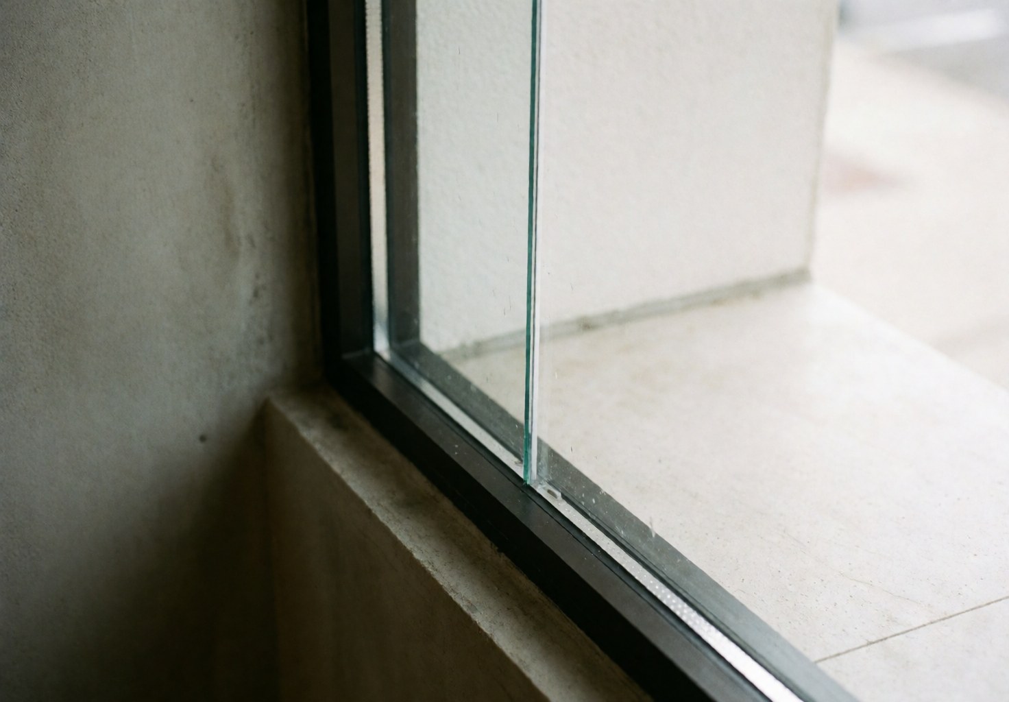 Spotless commercial window with black frame and concrete wall, illuminated by natural light, ideal for window cleaning services.
