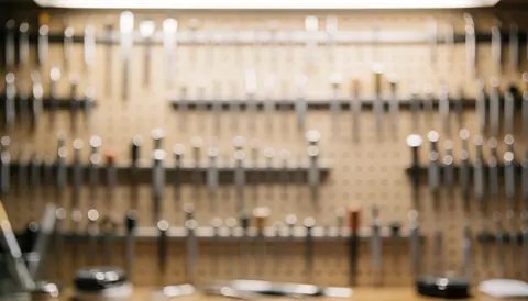 Watchmaking tools hanging on a wooden wall with warm lighting and bokeh effect, suitable for text and logos.
