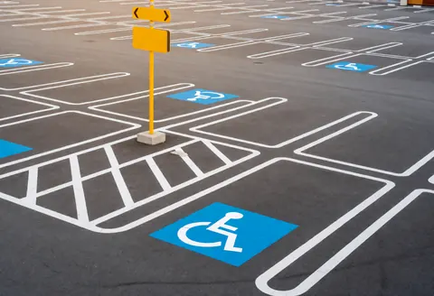 Empty themed parking lot with marked disabled spaces and yellow signage on clean illuminated pavement