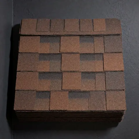 Stacked brown asphalt shingles arranged in a grid pattern, showing granular texture and overlap design on a charcoal gray background.