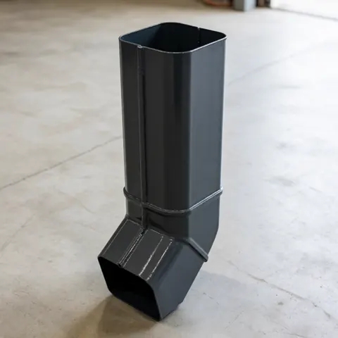 Gray carbon rectangular metal drainage pipe resting on a concrete surface, suitable for roofing and exterior drainage projects.