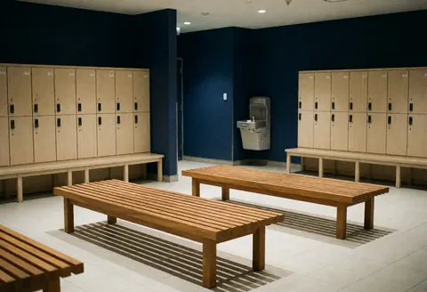 Empty wooden benches in a climbing gym rest area with blue lockers and a water fountain against blue walls