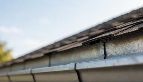Close-up of a metal gutter and roof tiles under natural light with a blurred background suitable for commercial text overlays