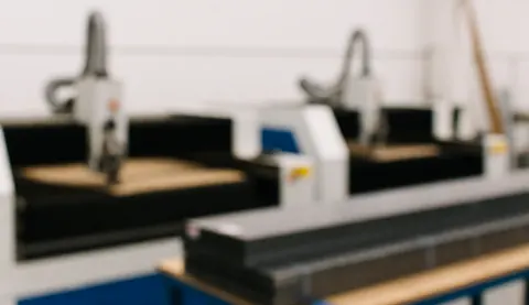 Blurred background of an industrial metal cutting workshop with machinery and steel stacks, soft professional lighting for text overlay